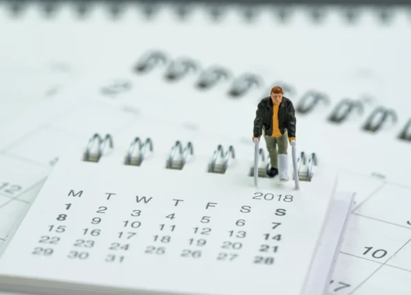 small figurine of a man on crutches walking on a calendar
