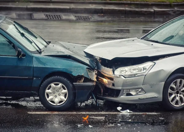 Two cars involved in a head-on collision on a rainy street.