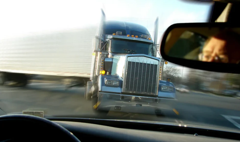 View over a car’s dashboard of an oncoming semi-truck.